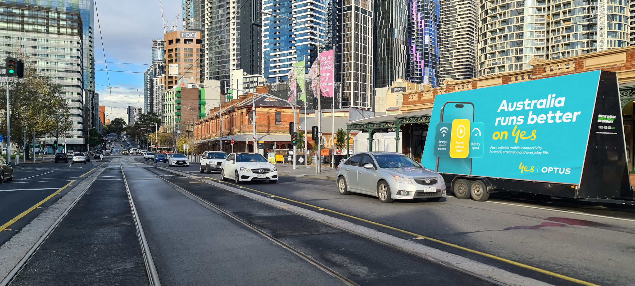 Optus B Optus mobile billboard near Melbourne transport hub targeting morning commuters